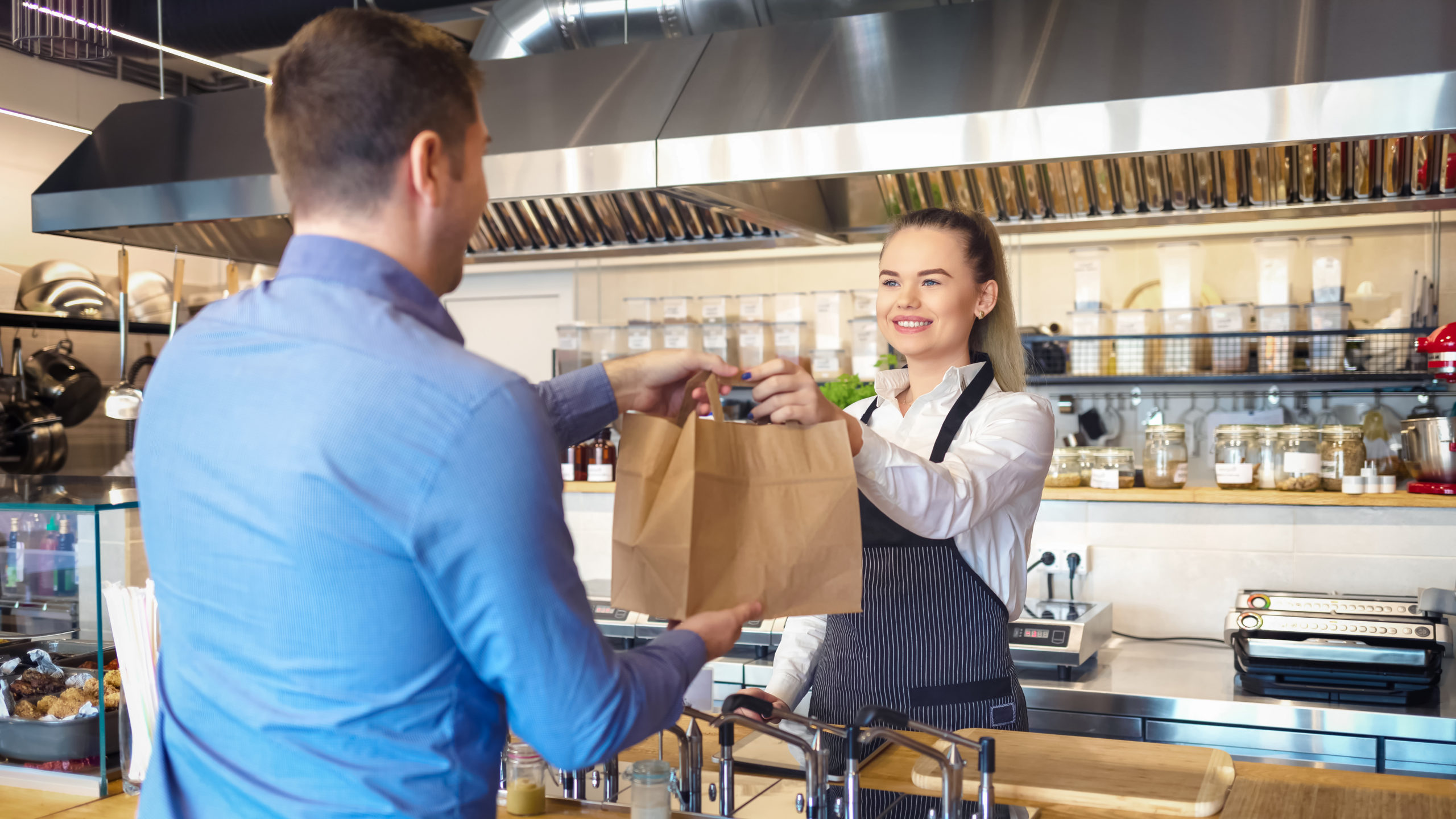 Happy,Waitress,Wearing,Apron,Serving,Customer,At,Counter,In,Small
